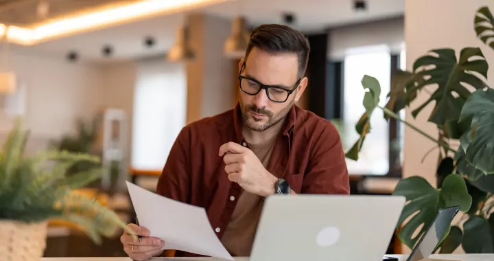 millennial man using laptop sitting at the table in a home office